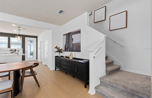 dining area featuring light wood-style flooring, visible vents, stairway, and baseboards