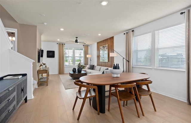 dining room featuring ceiling fan, recessed lighting, a fireplace, baseboards, and light wood-style floors