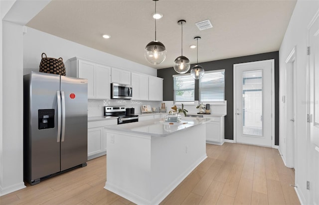 kitchen with visible vents, white cabinets, appliances with stainless steel finishes, light countertops, and light wood-style floors