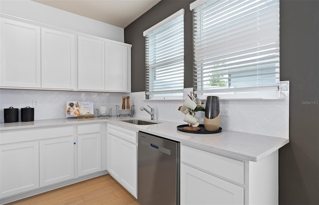 kitchen with tasteful backsplash, light wood-style floors, white cabinets, a sink, and dishwasher