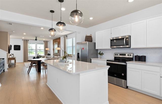 kitchen with a kitchen island, visible vents, appliances with stainless steel finishes, light wood-type flooring, and decorative backsplash