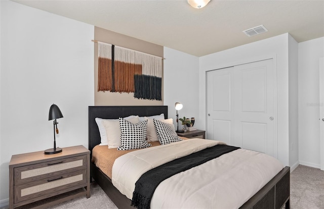 bedroom with baseboards, visible vents, a closet, and light colored carpet