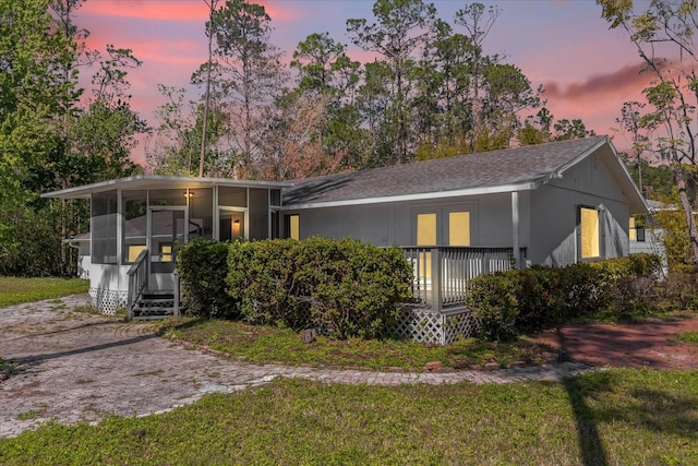 view of front facade featuring a yard, covered porch, and a sunroom