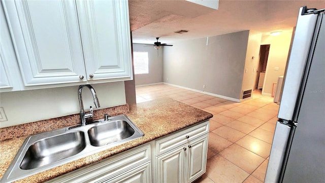 kitchen with light tile patterned floors, freestanding refrigerator, a sink, and visible vents