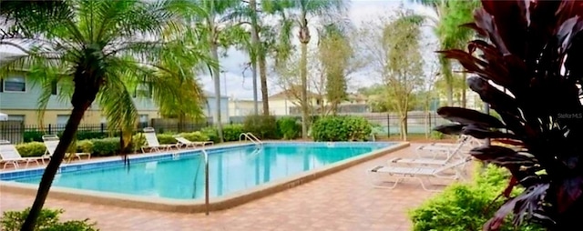 community pool with a patio and fence