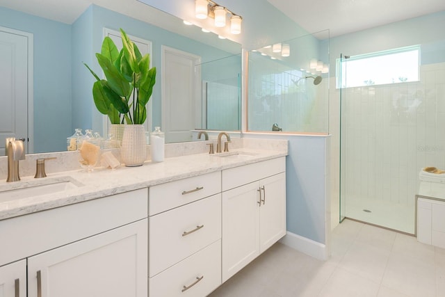 bathroom with double vanity, a sink, baseboards, and a walk in shower