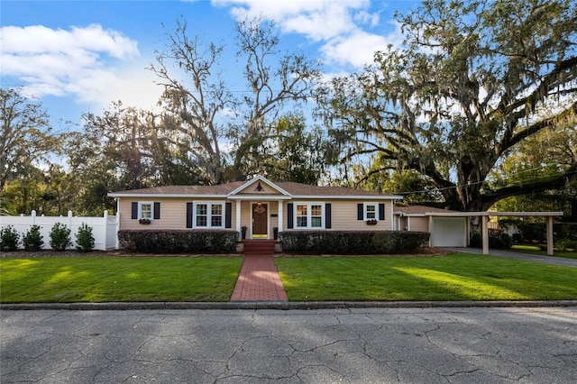 ranch-style home featuring aphalt driveway, an attached carport, a garage, fence, and a front yard