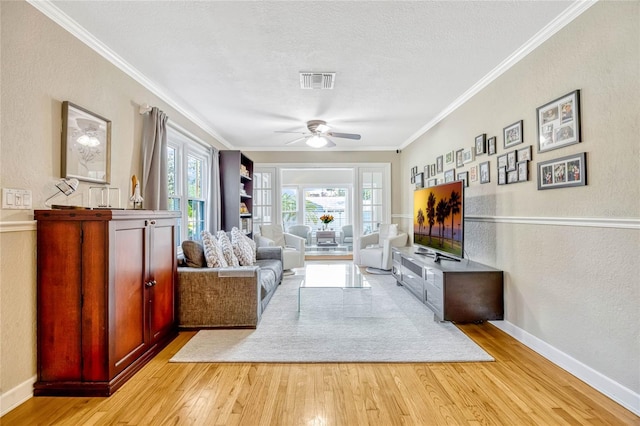 living room featuring baseboards, visible vents, crown molding, and light wood finished floors