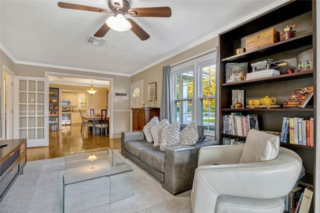 living room featuring ceiling fan, ornamental molding, wood finished floors, and visible vents