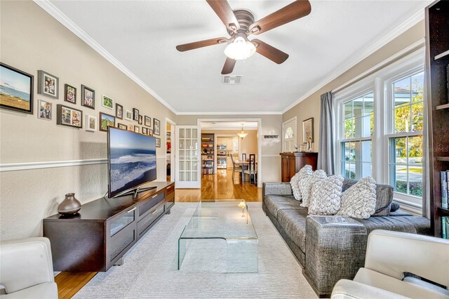 living area with ceiling fan, wood finished floors, visible vents, french doors, and ornamental molding