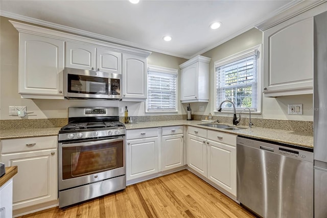 kitchen featuring stainless steel appliances, recessed lighting, light wood-style flooring, white cabinetry, and a sink