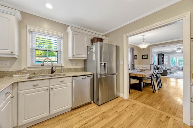 kitchen featuring appliances with stainless steel finishes, white cabinets, a sink, light wood-type flooring, and plenty of natural light