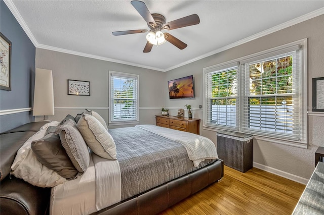 bedroom featuring light wood finished floors, baseboards, a ceiling fan, ornamental molding, and a textured ceiling