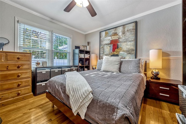 bedroom featuring ornamental molding, a textured wall, and light wood-style floors