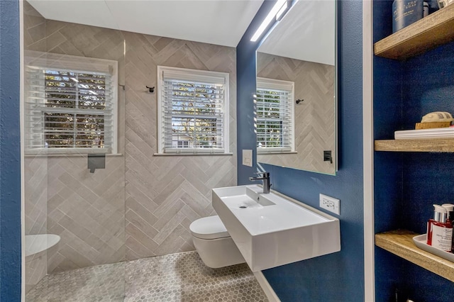 bathroom featuring a sink, a tile shower, and toilet