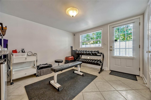 exercise room with light tile patterned flooring and baseboards