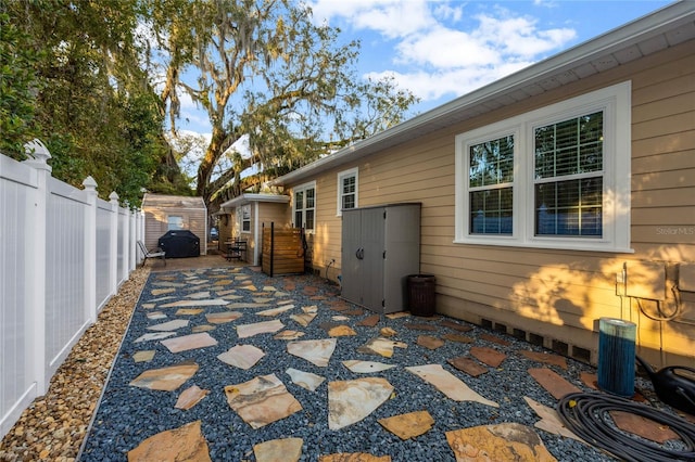 view of home's exterior featuring a storage unit, a patio area, fence, and an outdoor structure