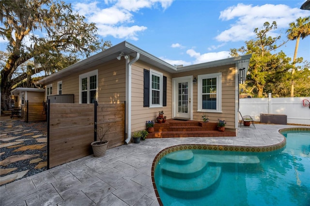 rear view of property with fence, a fenced in pool, and a patio