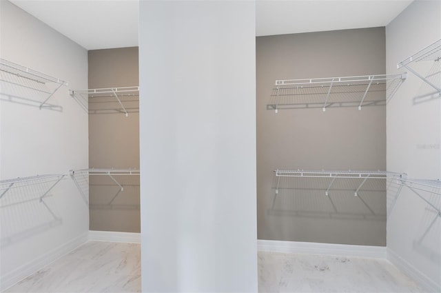 walk in closet featuring marble finish floor