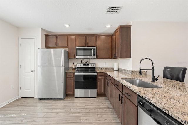 kitchen featuring visible vents, light stone counters, stainless steel appliances, a sink, and recessed lighting