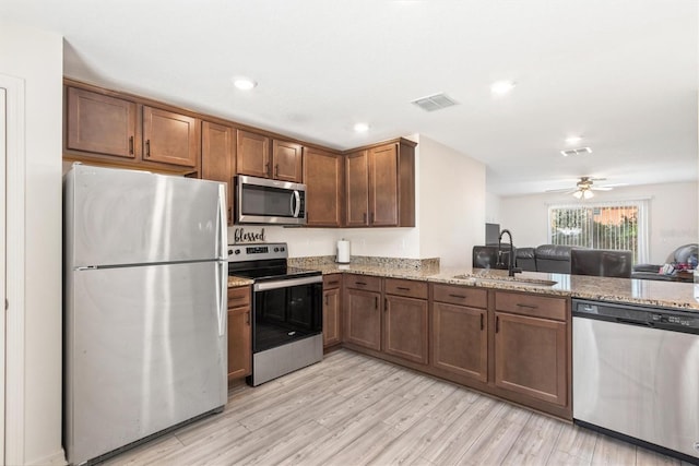 kitchen with light stone countertops, visible vents, stainless steel appliances, and a sink