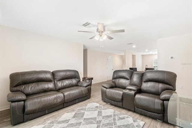 living room featuring light wood-style floors, baseboards, visible vents, and a ceiling fan