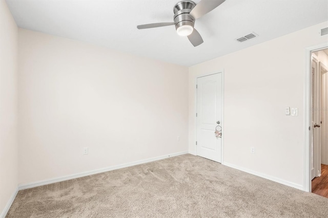 carpeted empty room with a ceiling fan, visible vents, and baseboards