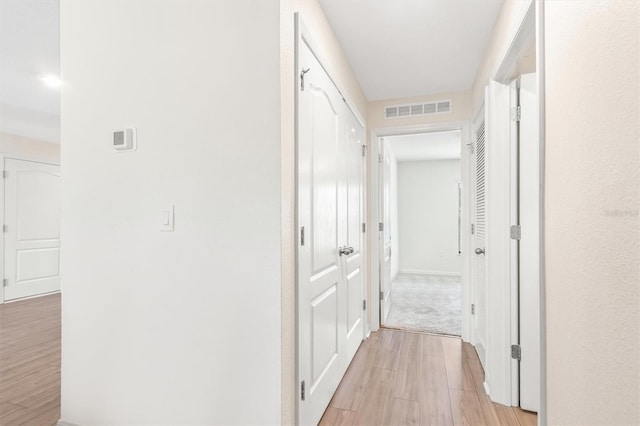 hall featuring light wood-style floors and visible vents