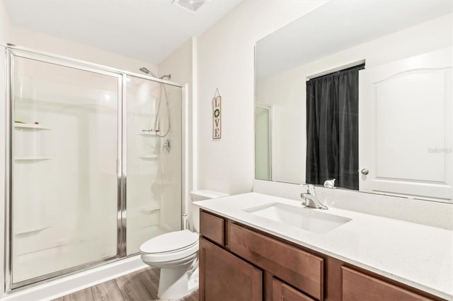 full bathroom featuring toilet, a stall shower, wood finished floors, and vanity