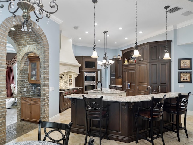 kitchen featuring a spacious island, stainless steel double oven, premium range hood, and ornamental molding