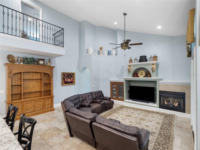 living room featuring arched walkways, a fireplace, recessed lighting, a towering ceiling, and a ceiling fan