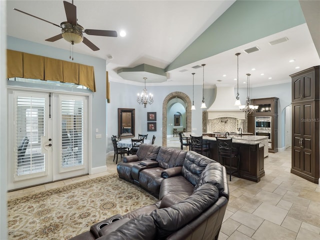 living room with visible vents, arched walkways, ornamental molding, high vaulted ceiling, and ceiling fan with notable chandelier