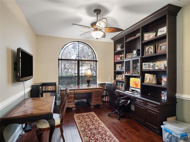 home office with dark wood-type flooring and a ceiling fan