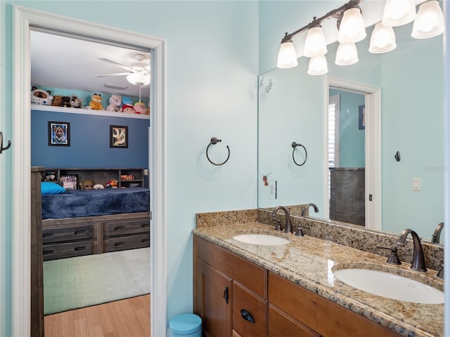 ensuite bathroom featuring connected bathroom, double vanity, a sink, and wood finished floors