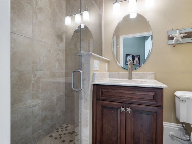 bathroom featuring toilet, a shower stall, and vanity