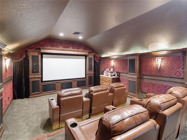 home theater featuring visible vents, carpet, vaulted ceiling, a textured ceiling, and a decorative wall