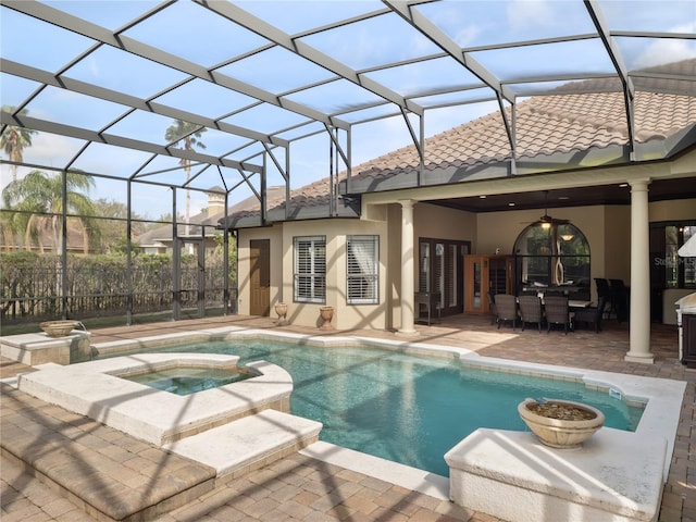 view of swimming pool with a pool with connected hot tub, glass enclosure, a patio, and ceiling fan