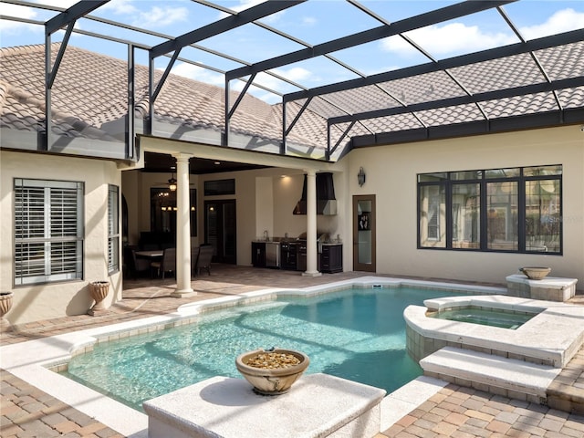 view of pool featuring ceiling fan, glass enclosure, area for grilling, a pool with connected hot tub, and a patio area