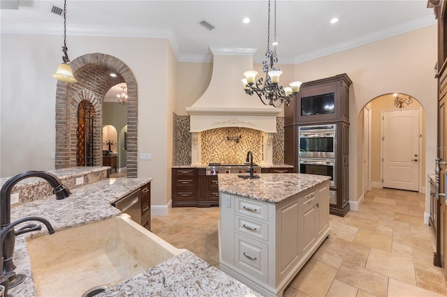 12860 Jacob Grace Ct, Windermere, FL 34786 - kitchen with arched walkways, double oven, a chandelier, an island with sink, and hanging light fixtures