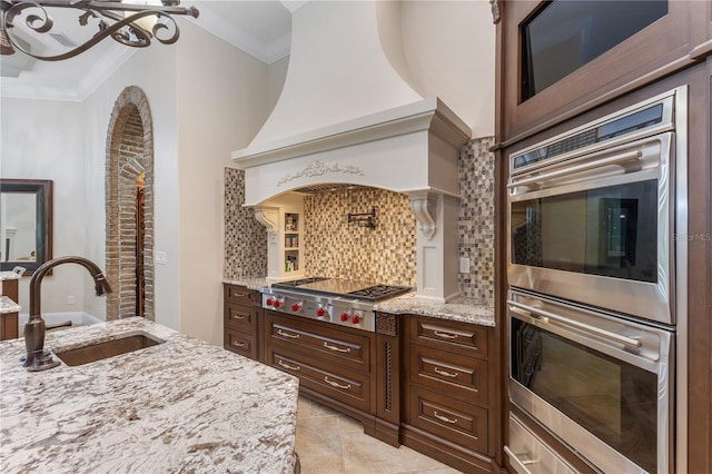 12860 Jacob Grace Ct, Windermere, FL 34786 - kitchen featuring a sink, appliances with stainless steel finishes, decorative backsplash, light stone counters, and ornamental molding
