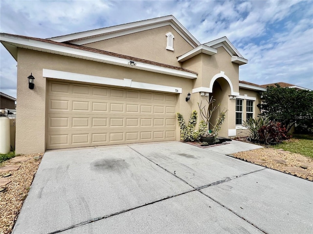 view of front of property featuring an attached garage, concrete driveway, and stucco siding