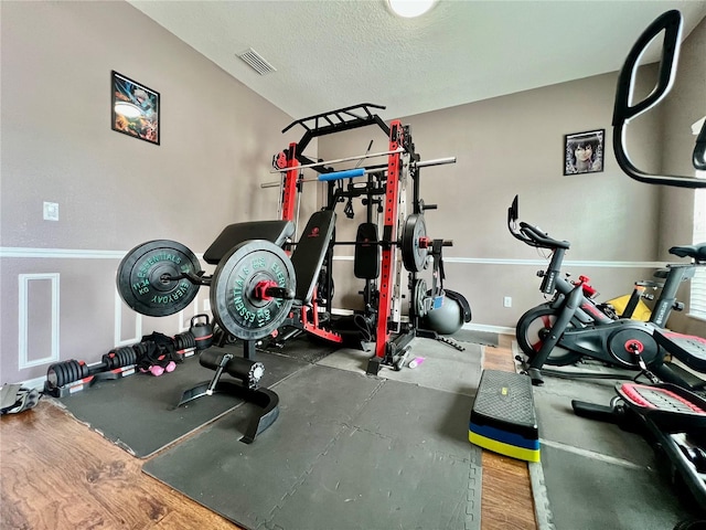 workout area featuring a textured ceiling, wood finished floors, and visible vents