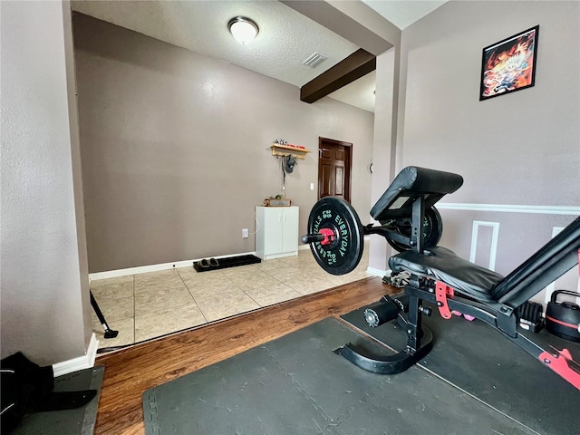 workout area with visible vents, a textured ceiling, baseboards, and wood finished floors