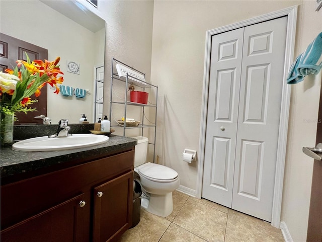 half bathroom featuring tile patterned flooring, baseboards, vanity, and toilet