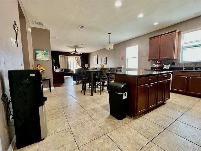 kitchen with dark countertops, visible vents, backsplash, and light tile patterned flooring