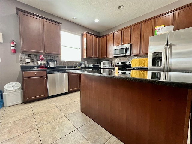 kitchen featuring light tile patterned floors, tasteful backsplash, stainless steel appliances, a textured ceiling, and recessed lighting