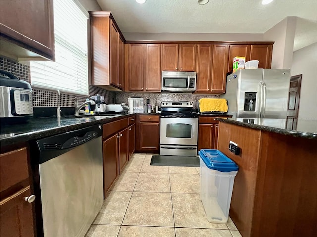 kitchen featuring appliances with stainless steel finishes, tasteful backsplash, a sink, and light tile patterned floors