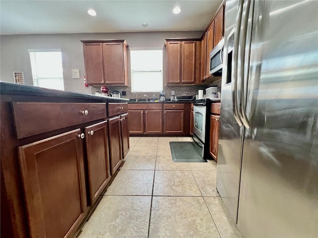 kitchen featuring tasteful backsplash, dark countertops, light tile patterned flooring, stainless steel appliances, and recessed lighting