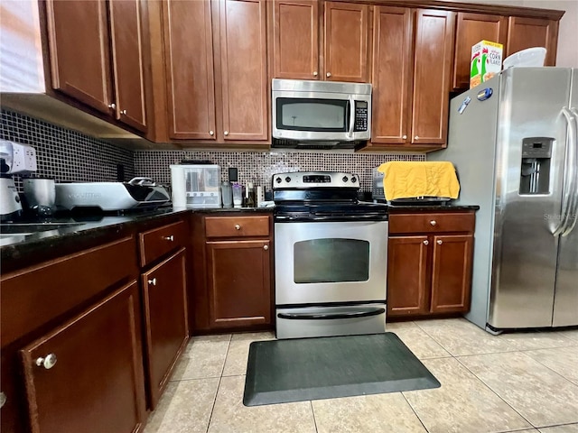 kitchen featuring appliances with stainless steel finishes, backsplash, dark stone countertops, and light tile patterned floors