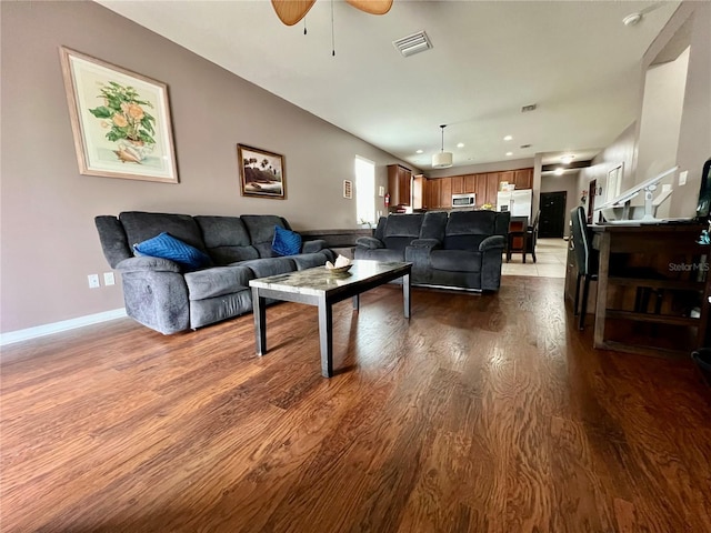 living room featuring dark wood finished floors, visible vents, a ceiling fan, baseboards, and stairs